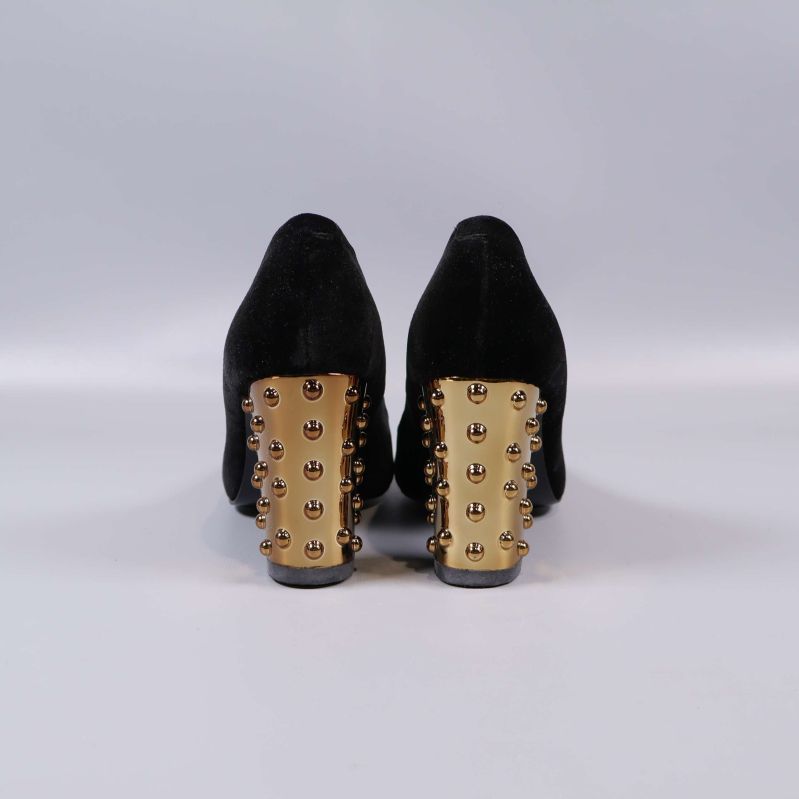 Baksidan av pumps med klack i guld och nitar