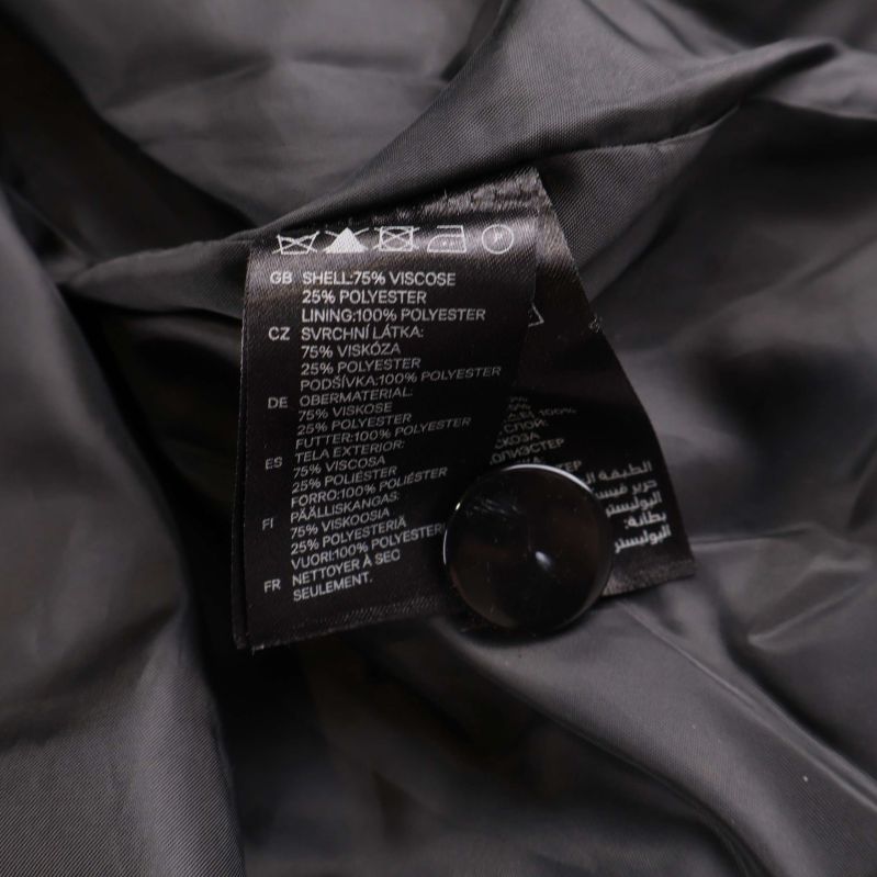 Materialetikett som visar sammansättning på svart klänning