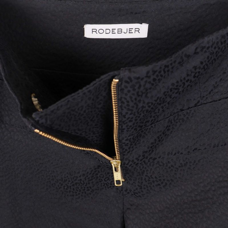 Närbild av dragkedja och Rodebjer logotyp i midjan