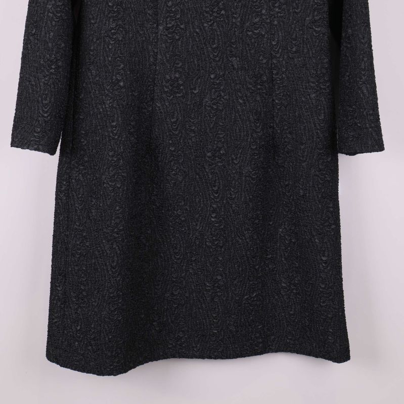 Nederdel av svart strukturerad klänning i närbild