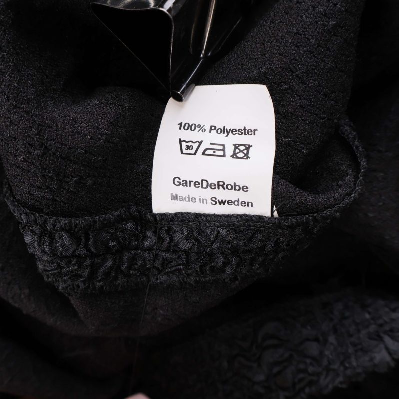 Materialetikett som visar 100% polyester GareDeRobe