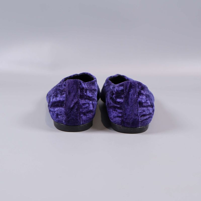 Baksidan av lila sammetsballerinor visas mot grå bakgrund