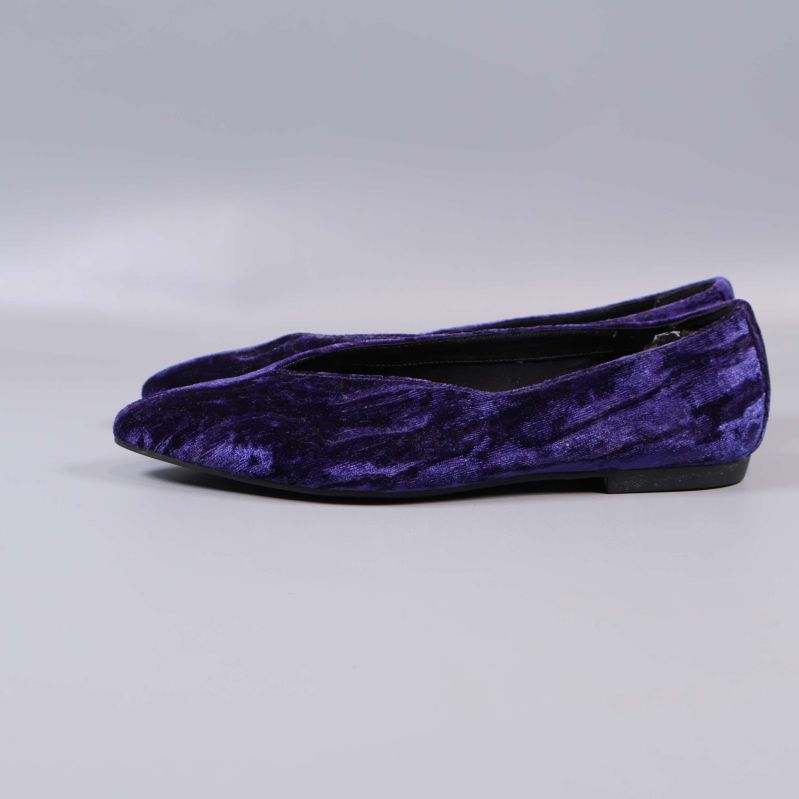 Sida av ballerinasko i lila sammet på grå bakgrund