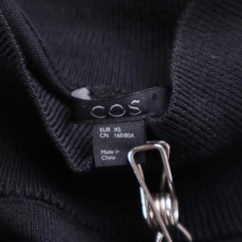 Storlekstag för svart klänning från COS, märkt XS