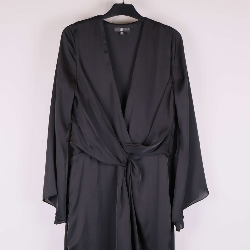 Närbild på v-ringning och knytskärp på svart klänning