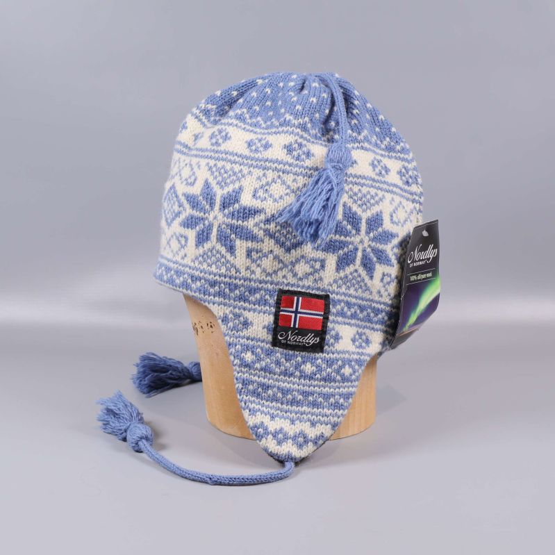 Blåvit stickad mössa med öronlappar och tofsar, norsk flagga framtill