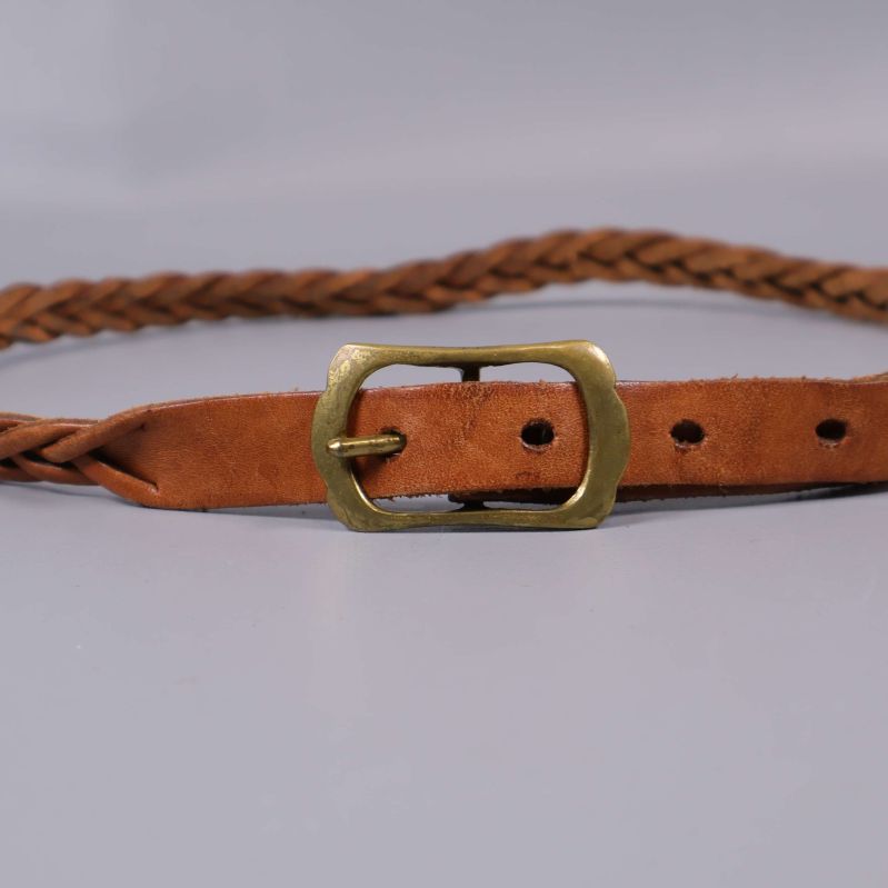 Närbild på bältets mässingsspänne och flätad rem