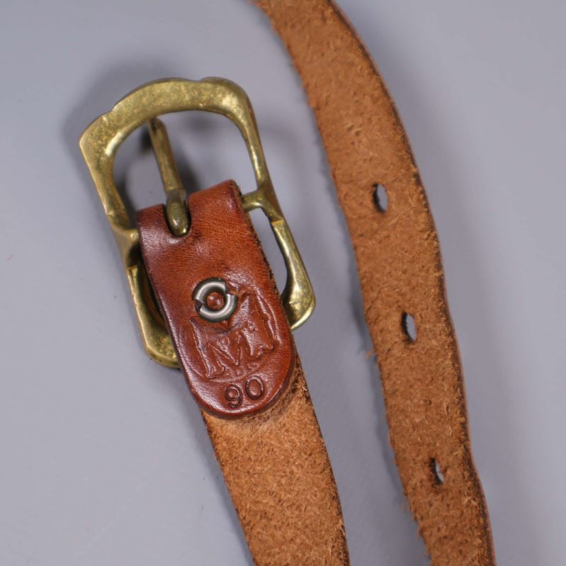 Närbild undersida av brunt bälte med präglad märkning