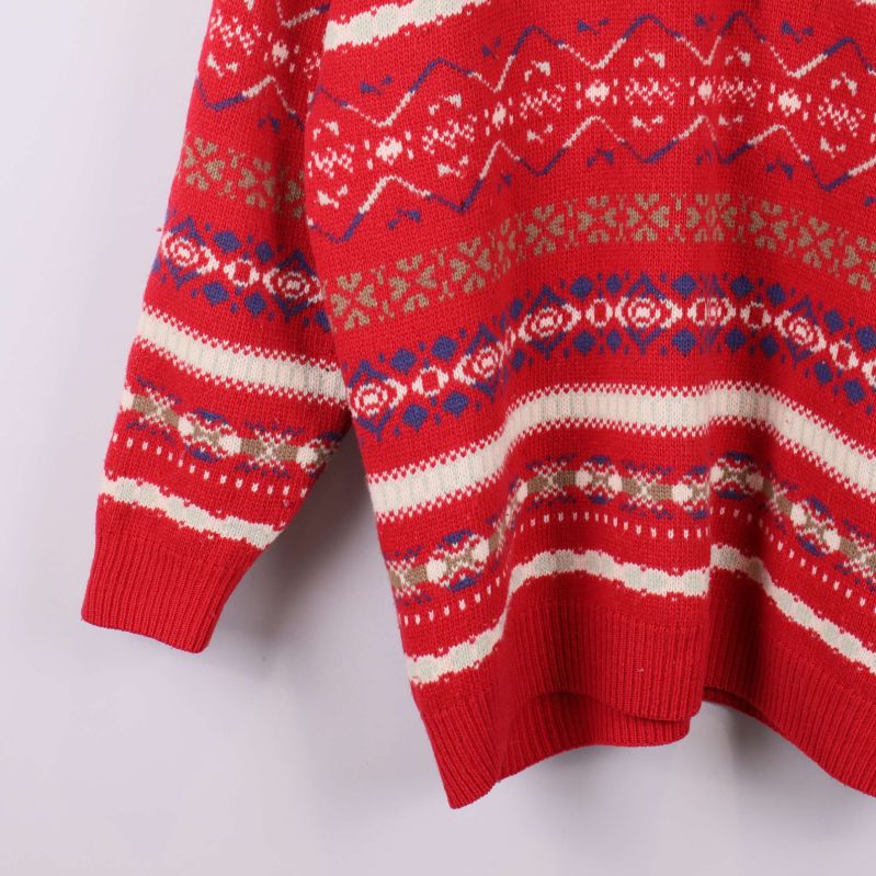 Ribbstickad ärm på röd mönstrad tröja i närbild