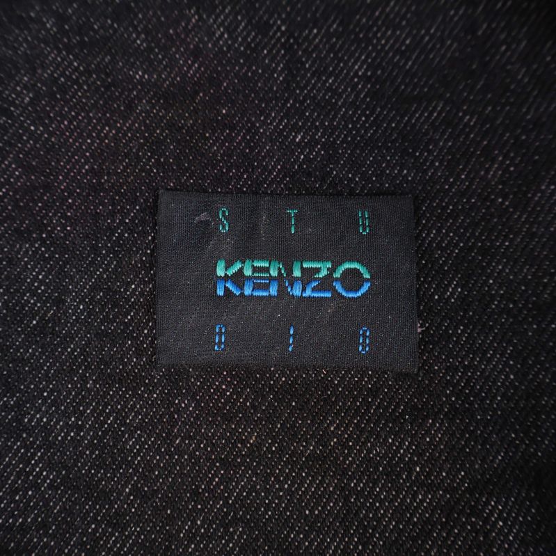 Närbild på Kenzo-etikett i blå text på svart tyg