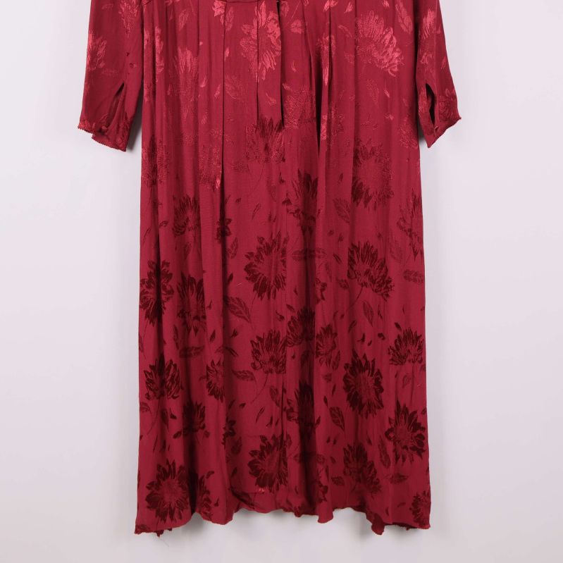 Nedre del av vinröd lång klänning med blommigt mönster