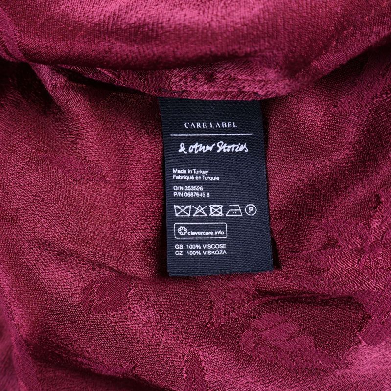 Material- och tvättetikett i vinröd mönstrad klänning