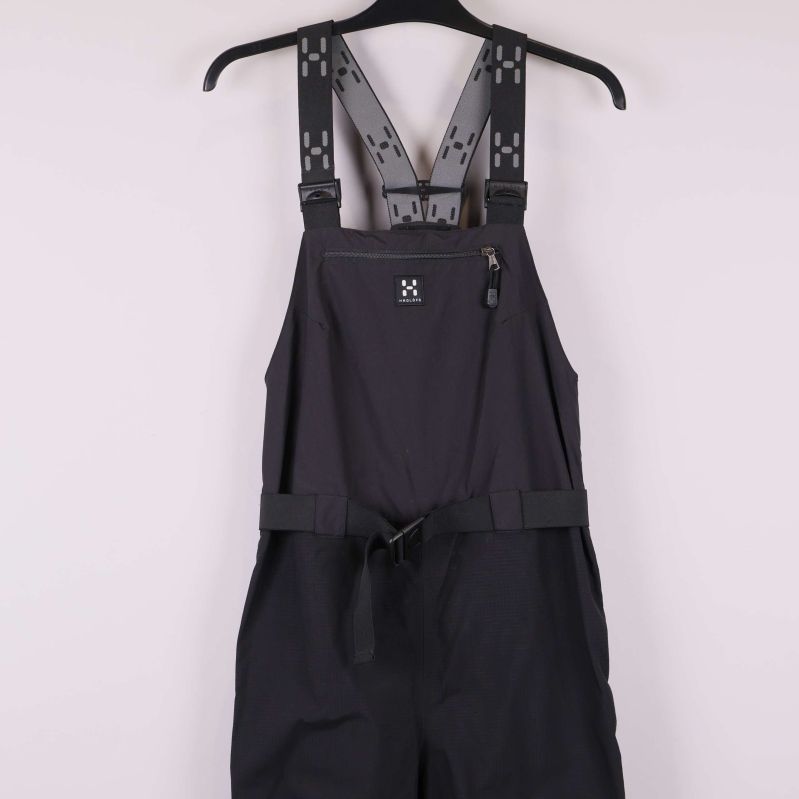 Närbild på midja och framficka på svart hängselbyxa