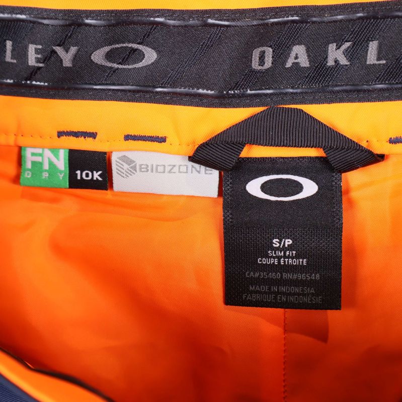 Närbild på orange och svart etikett med Oakley logo