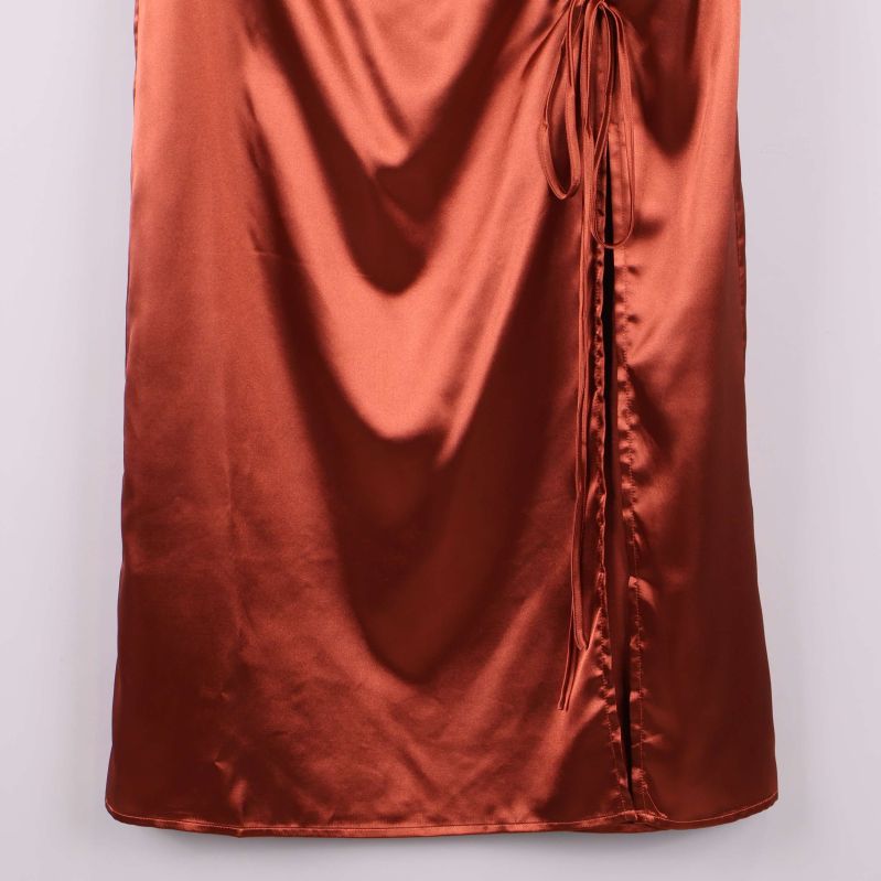 Nederkant av glänsande kopparfärgad satinkjol visas i närbild