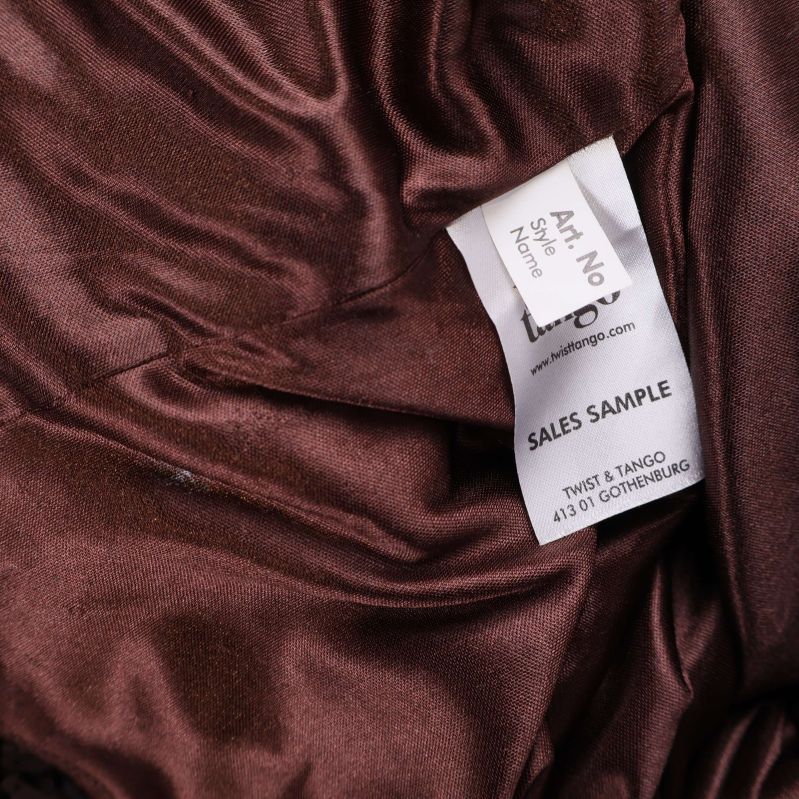 Textil-informationslapp i brun paljettklänning utan materialuppgift