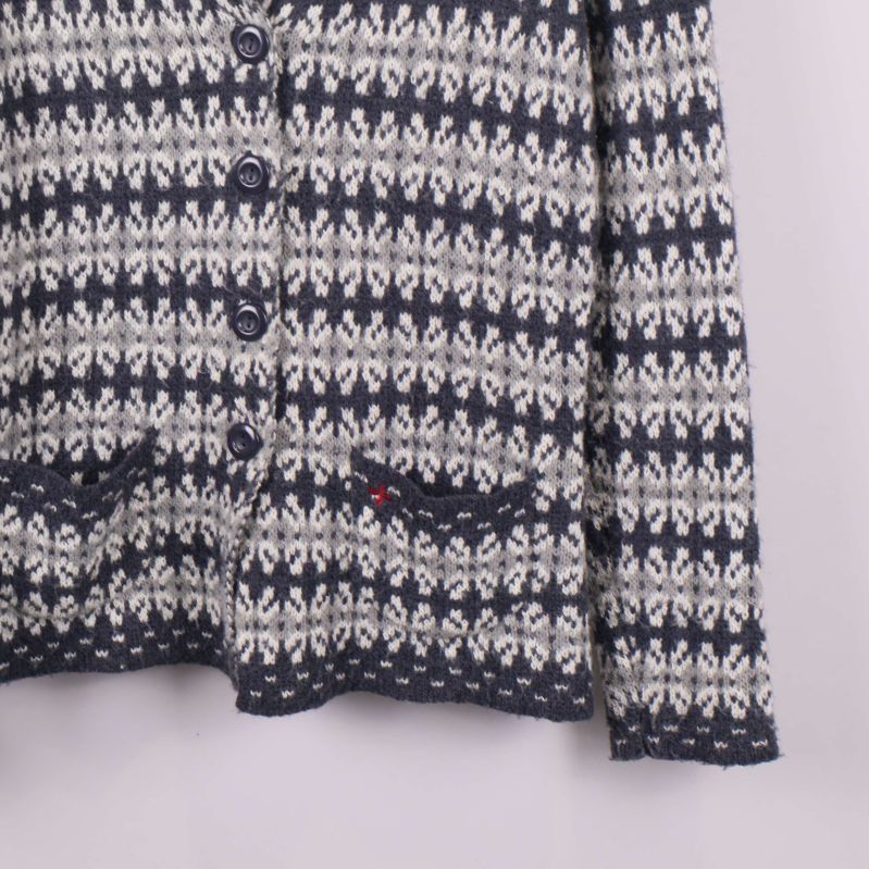 Närbild på koftans fickor med stickat mönster