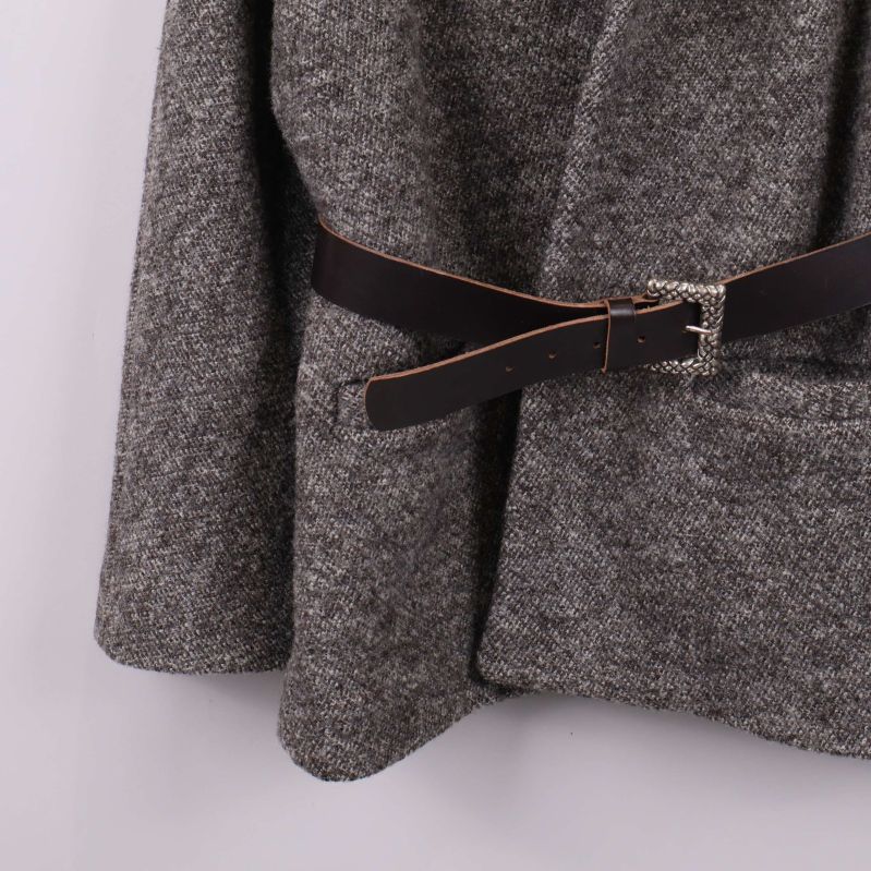 Närbild på fickdetalj och bältesdel av koftan