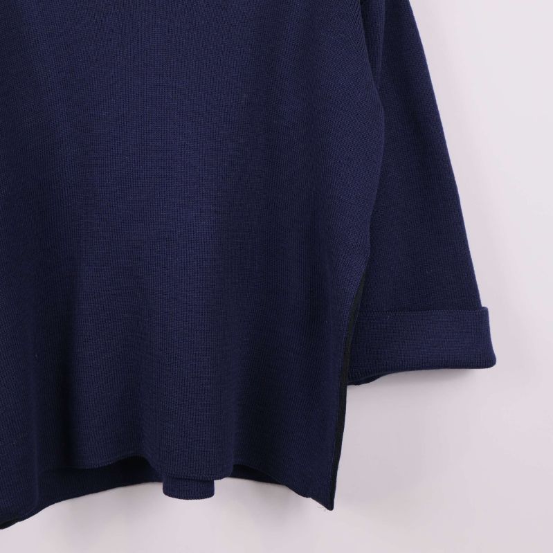 Detalj av uppvikt ärm och nederkant på mörkblå tröja