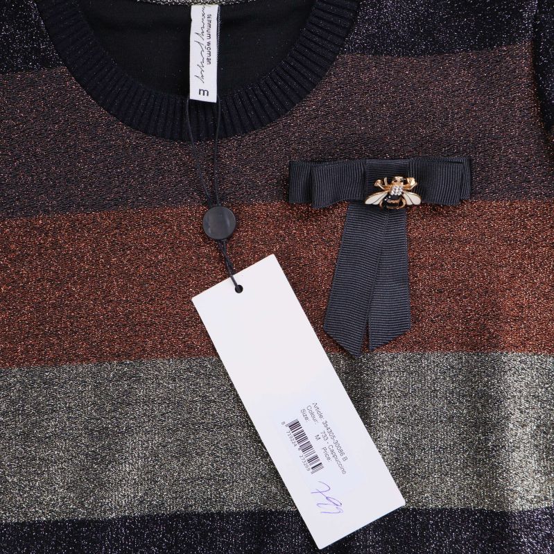 Nära av brosch, rosett och etikett framtill på t-shirt