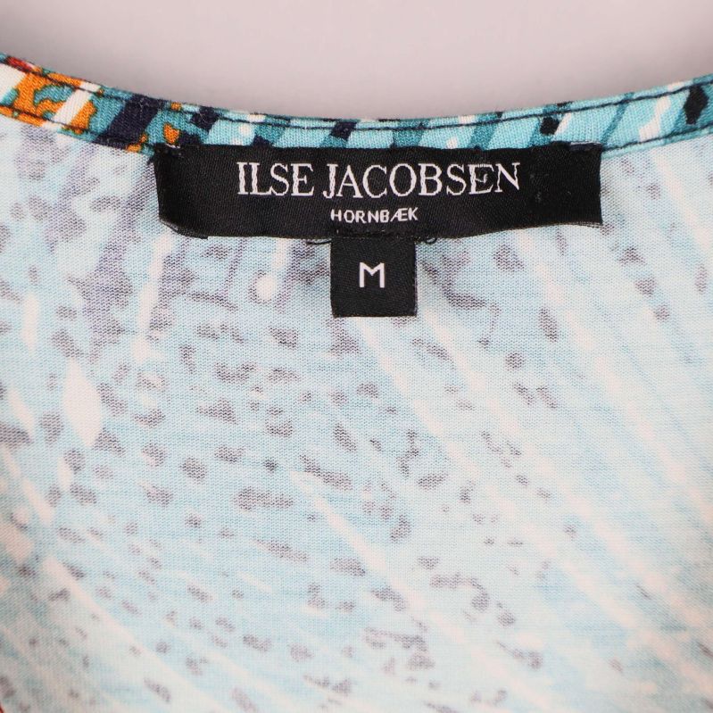 Närbild av Ilse Jacobsen-etikett i halsen på klänningen