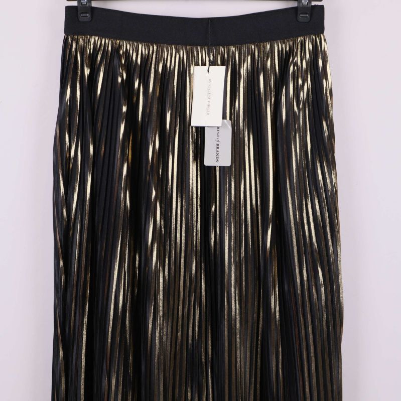 Detaljbild på plisserad kjol med guld och svart tyg och etiketter