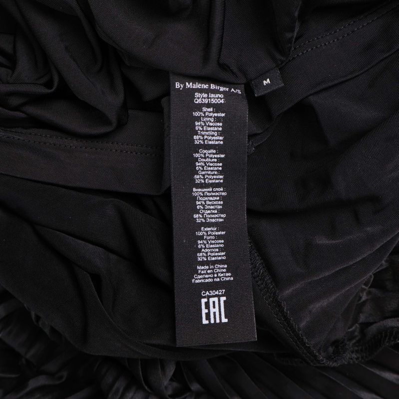 Tvättlapp med materialinfo i svart plisserad kjol