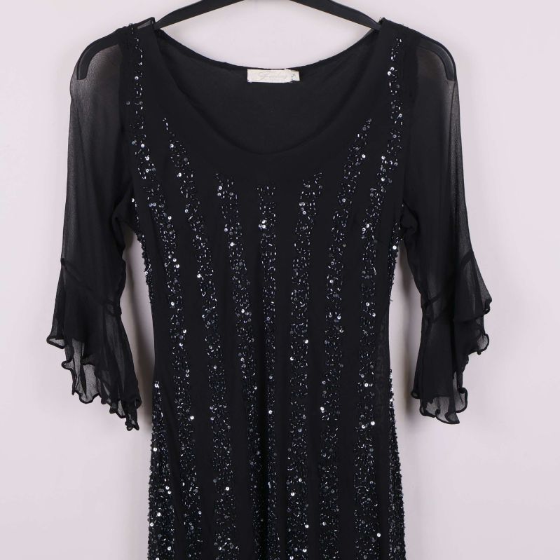 Halvbild på klänningens ovandel och ärmar med paljetter