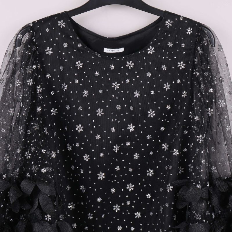 Närbild på toppen med glittermönster och rund halsringning