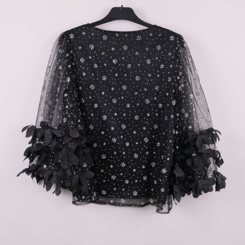 Baksida av svart topp med paljettmönster och bladapplikationer