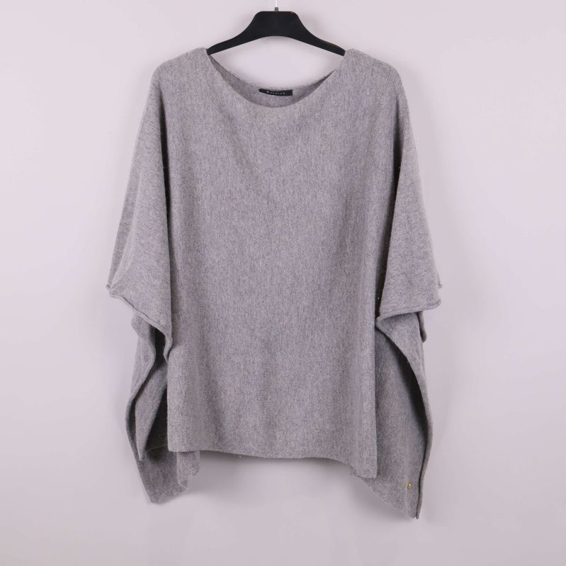 Ljusgrå poncho hängande på svart galge framifrån