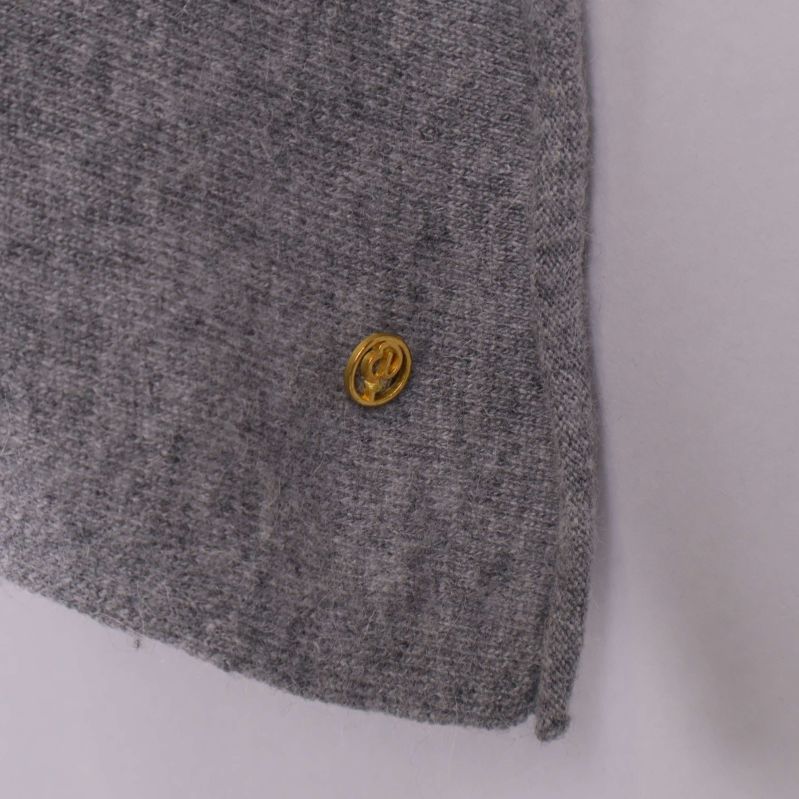 Liten guldig logga på ponchons nedre hörn