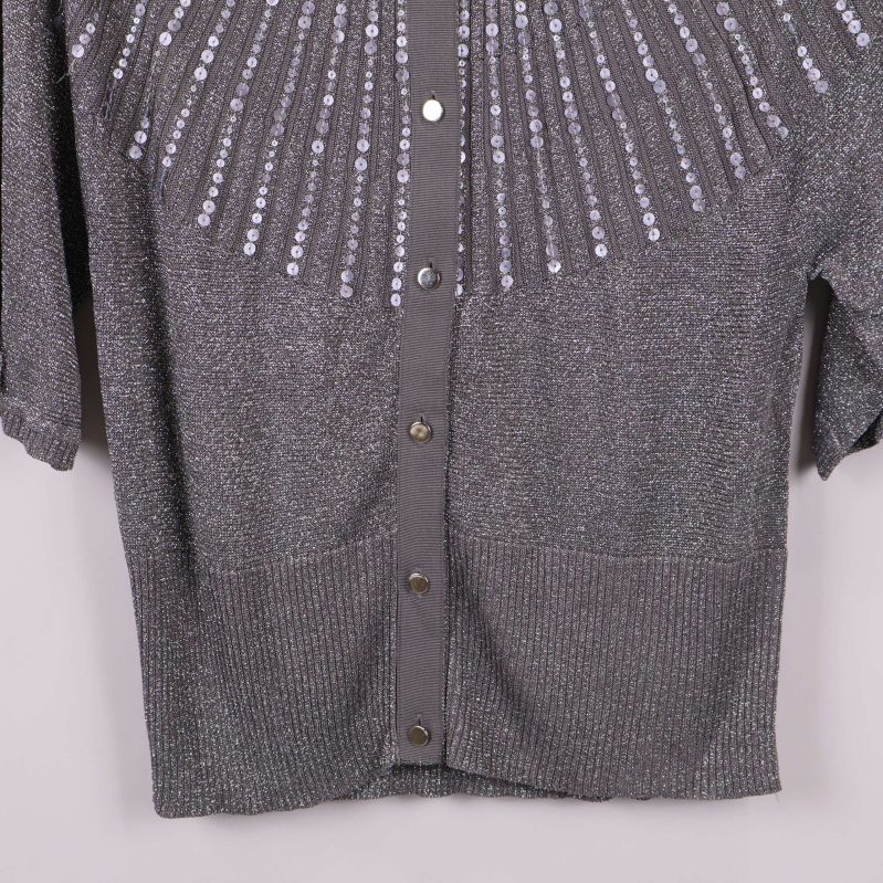 Nedre del av grå kofta med ribbad kant och glansig yta