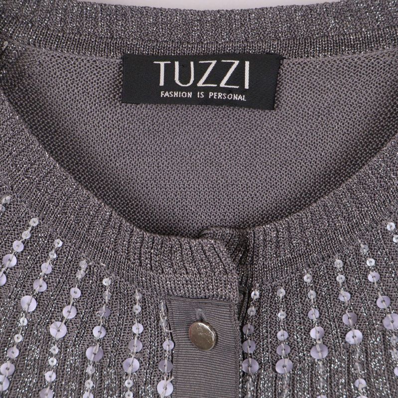 Närbild på TUZZI-märke i halsen på grå paljettkofta