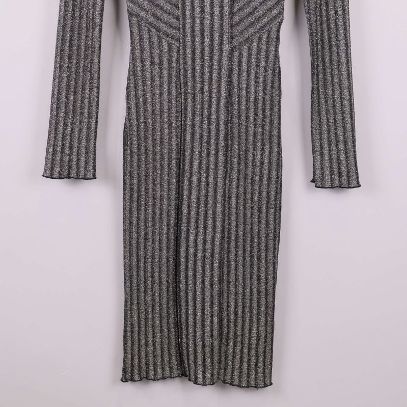 Nederdel av långärmad glittrig stickad klänning visas framifrån