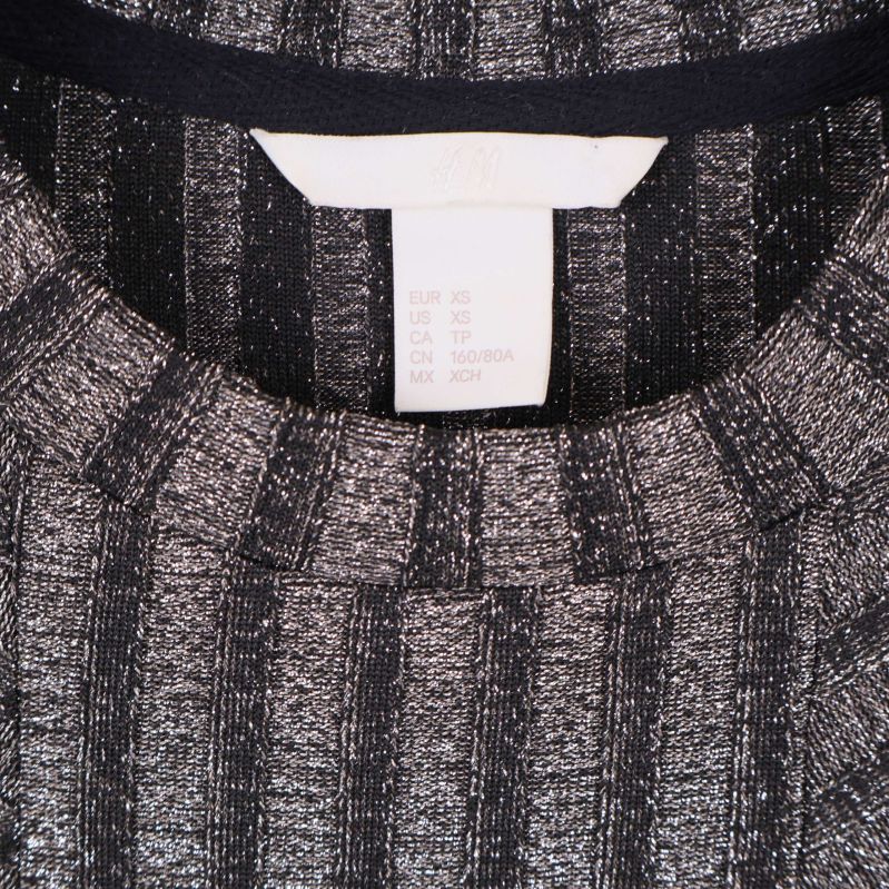 Närbild på hals och storleksetikett XS på ribbstickad klänning