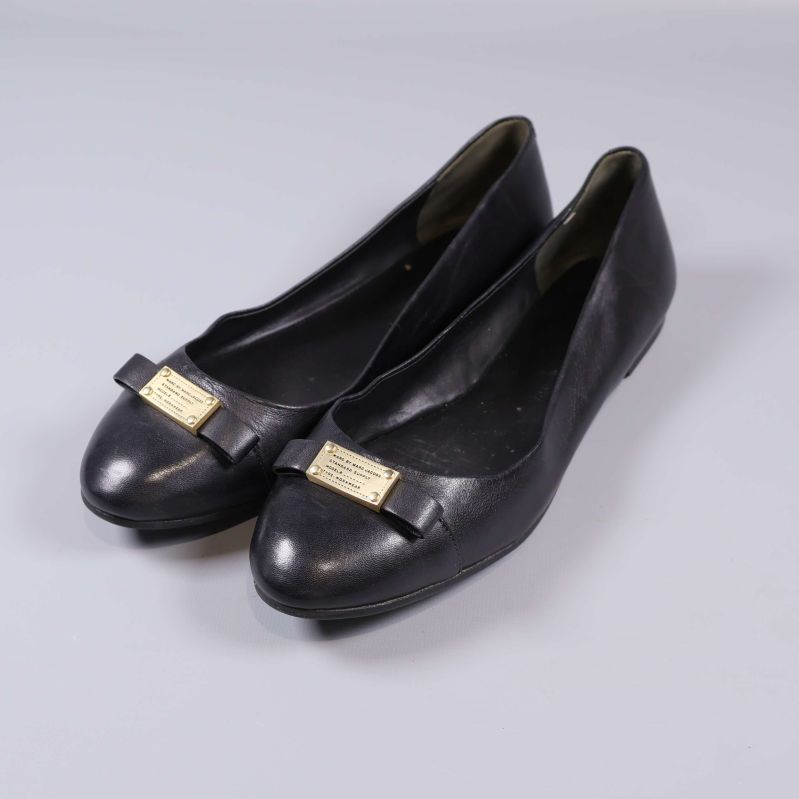 Par svarta ballerinaskor med dekorativ gulddetalj