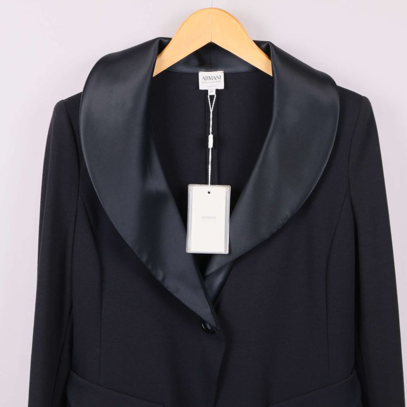 Närbild på kavajens breda slag i satin och ny etikett