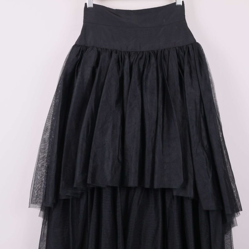 Närbild på volanger och lager på svart kjol