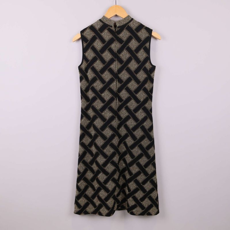 Baksida av ärmlös klänning med svart och guldigt mönster