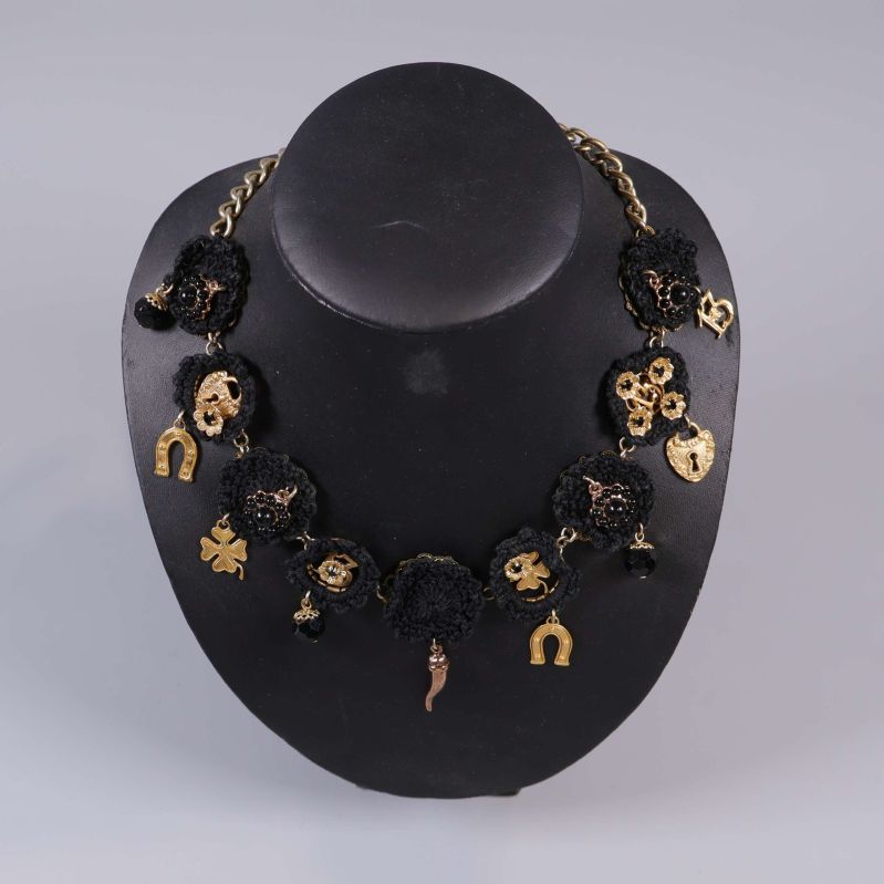 Halsband närbild med svarta blommor och berlocker