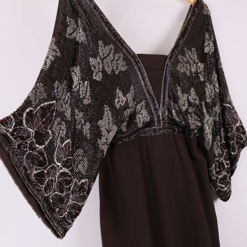 Närbild på v-ringning och dekorerade ärmar av klänning