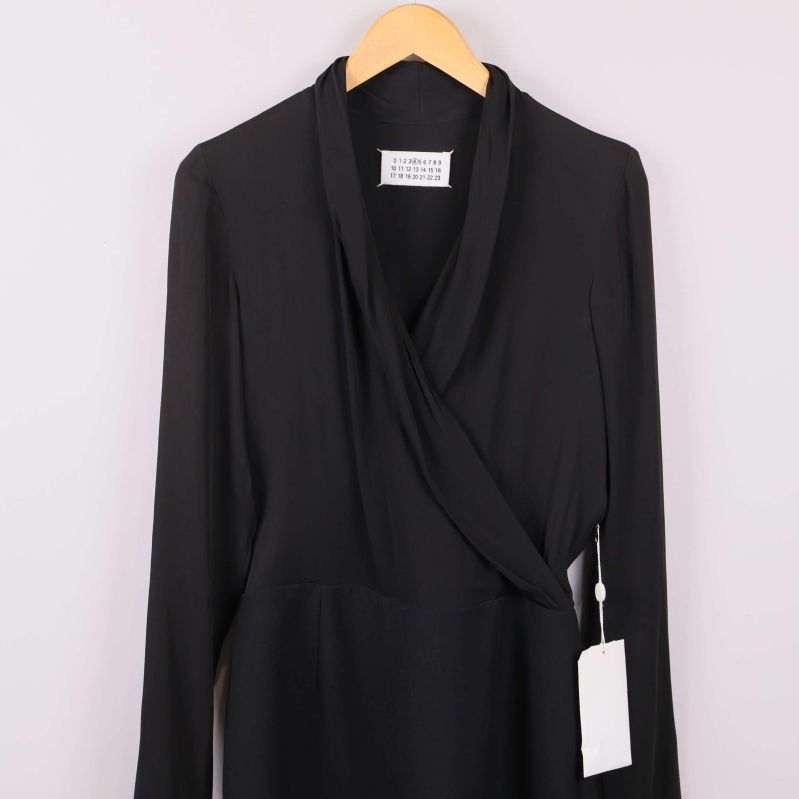 Närbild på överdelen av svart omlottklänning med etikett