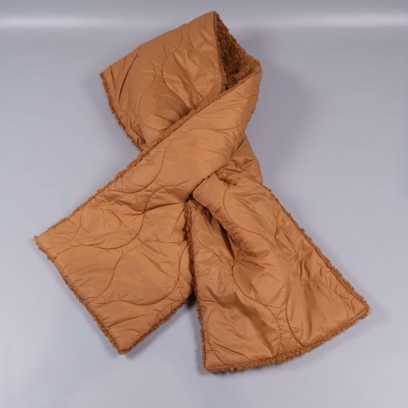 Halsduk i beige färg korslagd på en grå bakgrund