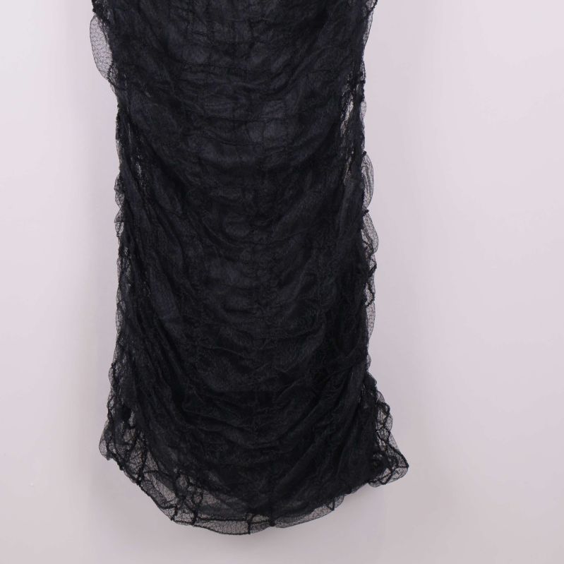 Närbild nedtill på draperad svart klänning