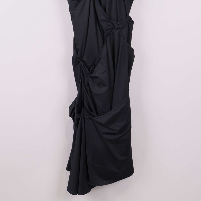 Närbild på nedre delen av draperad svart klänning