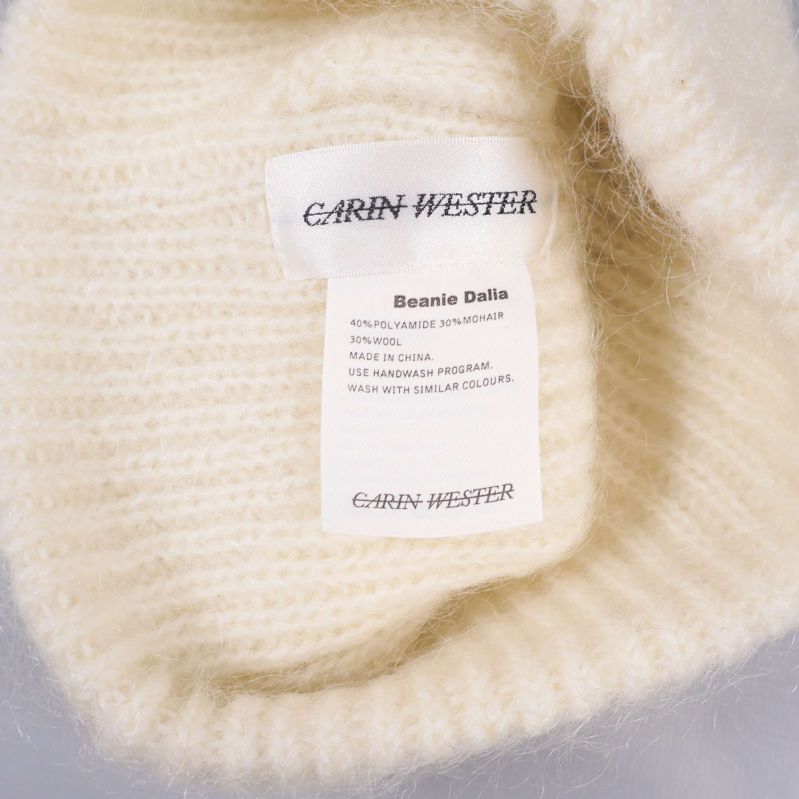 Inre etikett med Carin Wester-text i vit stickad mössa