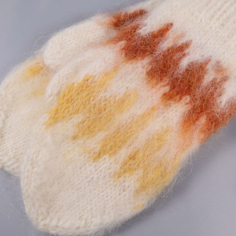 Närbild på stickade vantar med bruna och gula detaljer