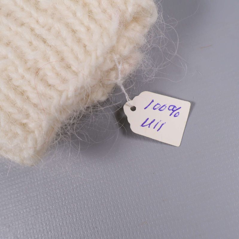 Etikett med texten 100% ull fastsydd på mudden