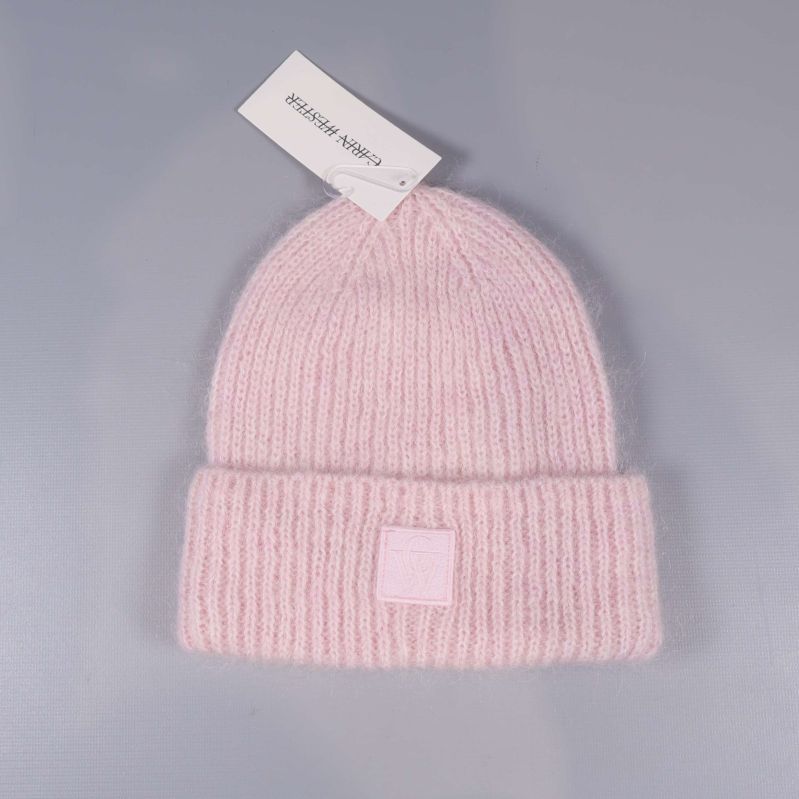 Ljusrosa ribbstickad mössa på grå bakgrund